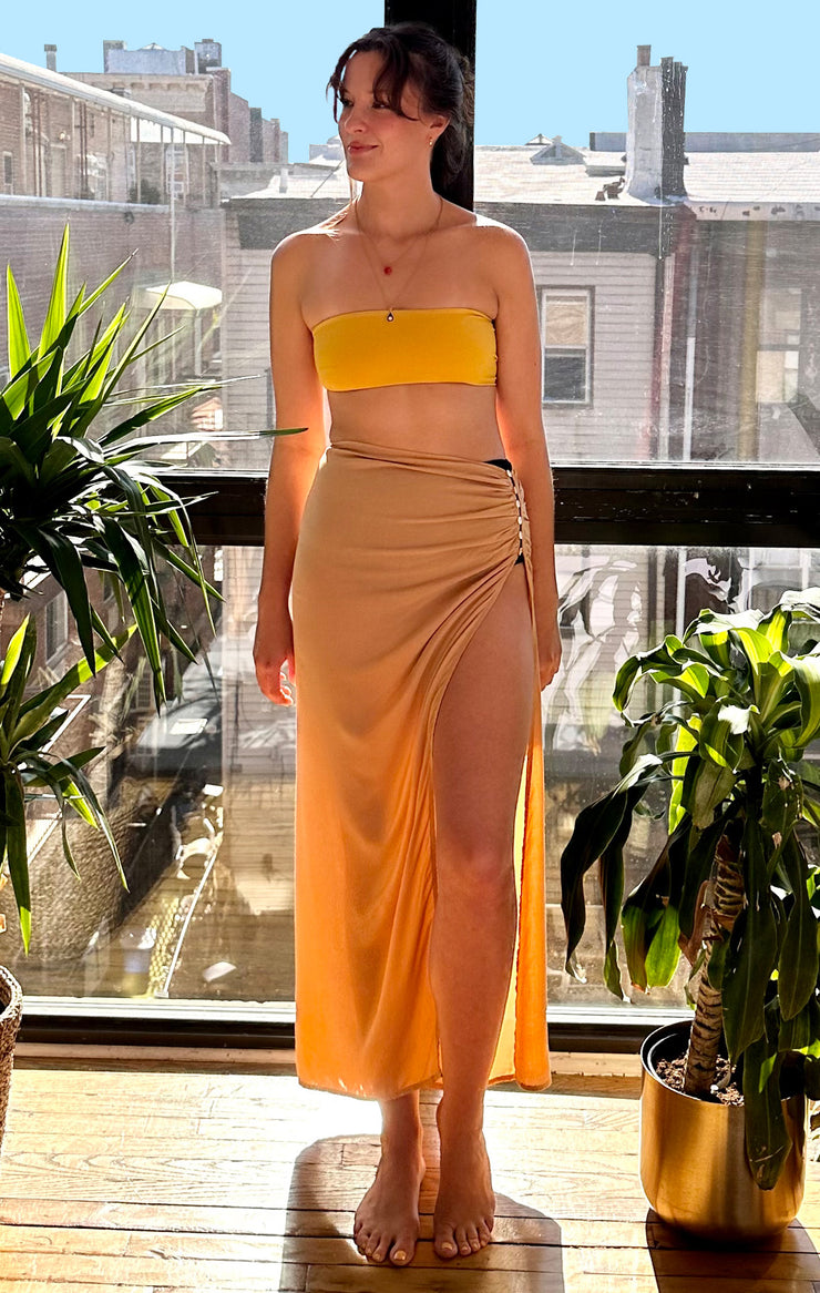 Long Skirt in sand color. Wear as a sarong, loungewear or out and about. Made from rayon. Sizes small to extra large. High cut slit with pearl buttons at the hip.